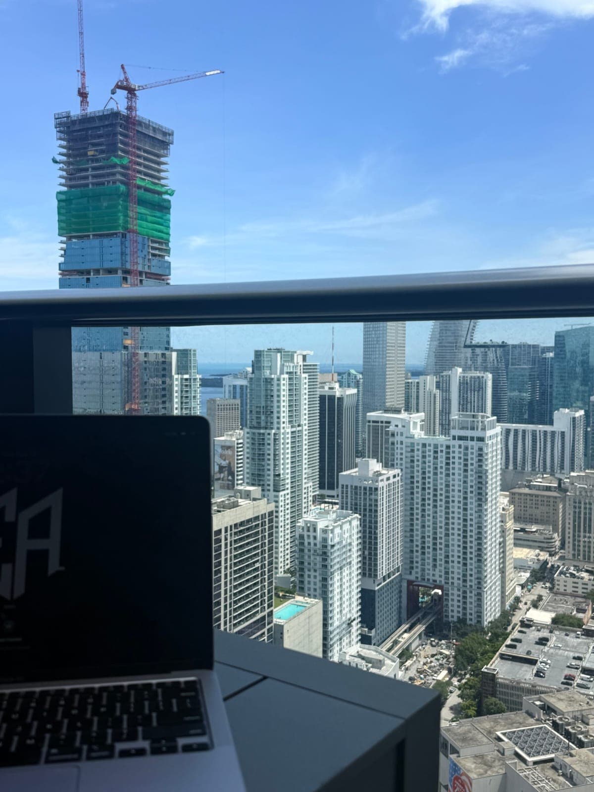 A laptop on a desk above a city skyline, with a tower going up